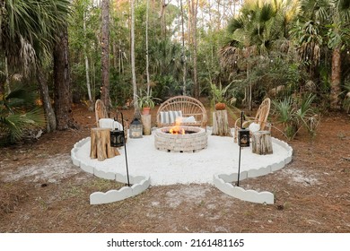 Fire Pit Bonfire Campsite In Tropical Backyard Woods With Rustic Wooden Branch Chairs Twinkle Lights Lantern Candles Palm Trees Stump Tables In Florida At Sunset