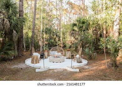 Fire Pit Bonfire Campsite In Tropical Backyard Woods With Rustic Wooden Branch Chairs Twinkle Lights Lantern Candles Palm Trees Stump Tables In Florida At Sunset