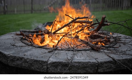 A fire pit with stacked logs on grass - Powered by Shutterstock