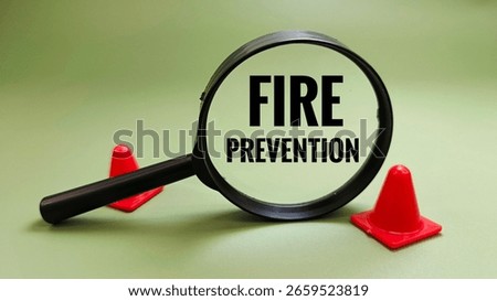 Fire prevention concept viewed through magnifying glass with safety cone. Focus on safety awareness, risk reduction, and emergency preparedness.