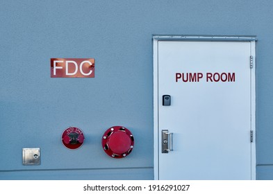 Fire Pump Room Door With Signs And Wall Fixtures On An Industrial Warehouse Exterior.