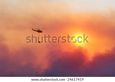 Fire rescue helicopter damping fire against sunset. Shot near Stellenbosch, Western Cape, South Africa.