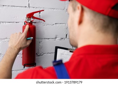 Fire Safety And Prevention - Service Worker Checking Extinguisher Pressure