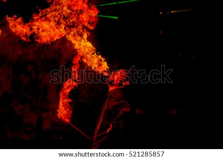 Fire show. Creative fiery artist, artist of extreme fire show show their skills and let firestorm of mouth, blows and breathes fire. Artist blowing fire from his mouth