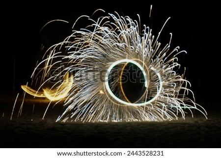 Fire show on the beach at night. Radius of sparkling light during the night show