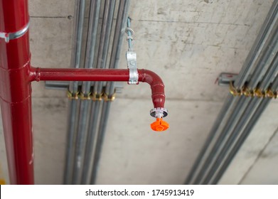 Fire Sprinkler System With Red Pipes Is Placed To Hanging From The Ceiling Inside Of An Unfinished New Building.Installation Of Conduits In Buildings.Conduit System In Building Under Construction.