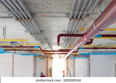 Fire Sprinkler System With Red Pipes Is Placed To Hanging From The Ceiling Inside Of An Unfinished New Building.Installation Of Conduits In Buildings.Conduit System In Building Under Construction.