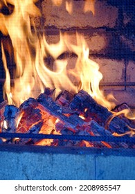 Fire In A Stone Fireplace In The Gazebo Of A Country House, Set Up For Barbecue, With A Protective Screen Made Of Metal Mesh. Rural Life.