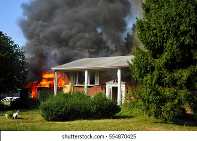 Fire At Suburban Home With Fireman In Bucket Appearing In Smoke Cloud Behind House