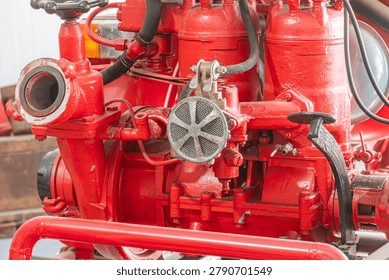 Fire suppression system components featuring vibrant red metal construction including valves, pipes, hoses and connectors showcasing wear and tear highlights robust design against harsh conditions.