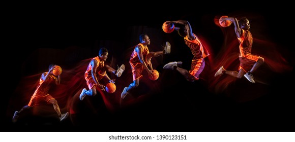 Fire tail or ways. African-american young basketball player of red team in action and neon lights over dark studio background. Concept of sport, movement, energy and dynamic, healthy lifestyle. - Shutterstock ID 1390123151