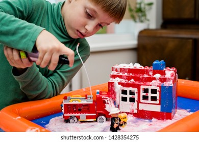 Fire Toys. Shaving Foam And Red Paint Fire On Plastic Block House. Kid With Fire Truck Pouring Water. 