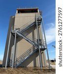 Fire Training Tower Featuring Exterior Metal Staircase And Elevated Platforms Against Clear Blue Sky, Representing Firefighter Training, Emergency Preparedness, And Safety Infrastructure