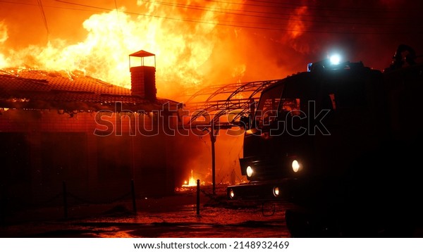 fire truck and flasher fire engine. fire on\
the roof of the house. a burning at building house . home insurance\
apartment concept. huge fire night blazes houses 911. property\
damage arson protection