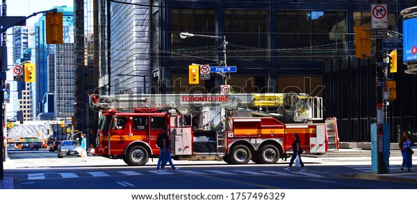 Fire truck on king street Toronto  with\
pedestrian crossing the street with cityscape in the background in\
Toronto, Ontario, Canada, June 13, 2020.\
