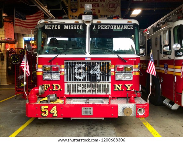 Fire truck in the parking lot in FDNY Engine\
54 Ladder 4 Battalion 9 on 8th Avenue in Midtown New York, waiting\
for a call. F.D.N.Y. firetrucks parked inside a station. New York,\
USA 10/01/2018