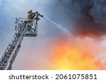 Fire truck telescopic tower. Fire inspector extinguishes fire. He pours flame from above. Extinguishing flame from telescopic tower. Firefighter on pull-out crane. Flame extinguishing from above