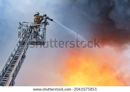 Fire truck telescopic tower. Fire inspector extinguishes fire. He pours flame from above. Extinguishing flame from telescopic tower. Firefighter on pull-out crane. Flame extinguishing from above