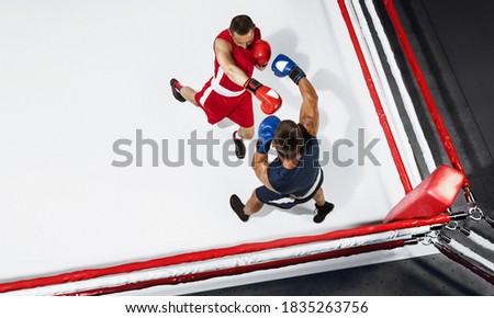 Fire. Two professional boxers boxing on white background on the ring, action, top view. Couple of fit muscular caucasian athletes fighting. Sport, competition, excitement and human emotions concept.