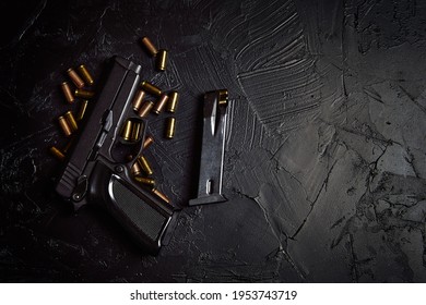 Firearms on dark background. Top view of gun and cartridge with bullets. Pistol for defense or attack. Concept of crime ammunition and physical evidence. Copy space. Weapons on concrete table.