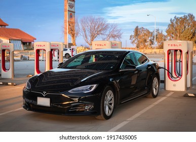 Firebaugh, USA - January 21, 2021: Black electric luxury Tesla Model S 75D car at a 250 kW Supercharger on California Highway 5