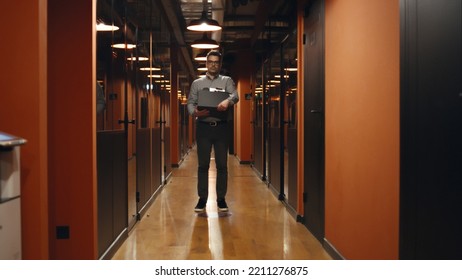 Fired Upset Man In Suit Walking Down In Office Hallway, Holding Box With Books And Personal Stuff, Saying Goodbye To Colleagues, Looking At Camera. Male Employee Leaving Marketing Company