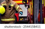 Firefighter in action at fire scene with hand reaching for fire truck door. Two fire engine appliances and smoke billowing through the air.