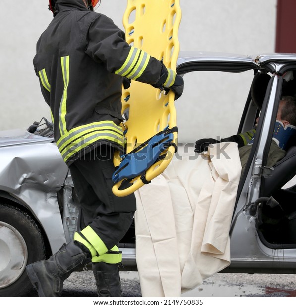 firefighter in action with the yellow stretcher\
after the road accident to transport the injured person who has\
just been rescued to the\
hospital