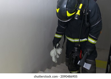 A Firefighter Climbs The Stairs, Holding A Teddy Bear Toy And A Hatchet For Opening Doors In His Hand