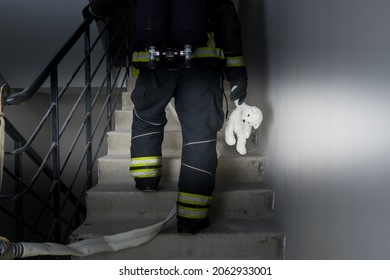 a firefighter climbs the stairs in incomplete darkness, holding a child's toy in his hand