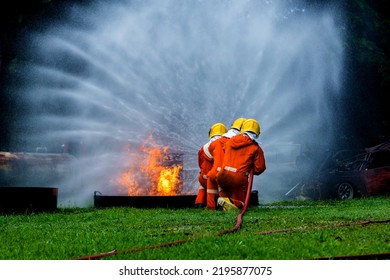 Firefighter Concept. Fireman Using Water And Extinguisher To Fighting With Fire Flame. Firefighters Fighting A Fire With A Hose And Water During A Firefighting Training Exercise 