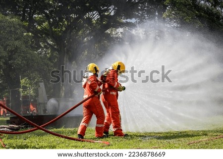 Firefighter Concept. Fireman using water and extinguisher to fighting with fire flame. firefighters fighting a fire with a hose and water during a firefighting training exercise