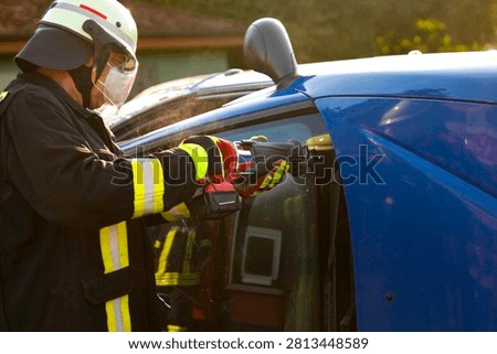 Firefighter during technical rescue training exercise using cordless reciprocating saw for car extrication

