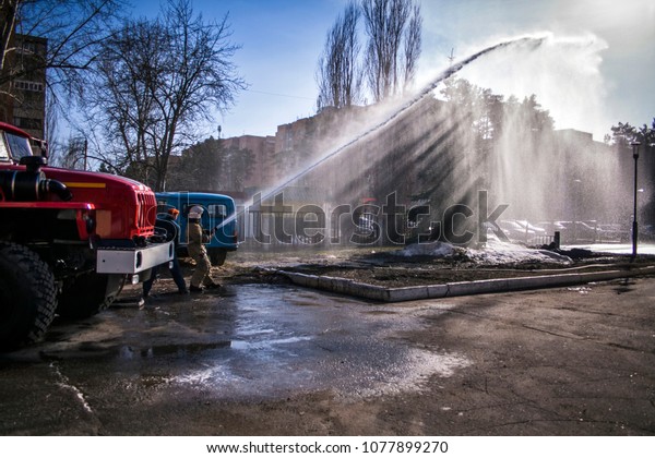 Firefighter and emergency\
situations mimic the fire on the background of a fire truck on a\
Sunny day.