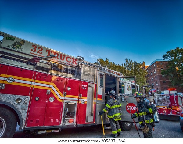 Firefighter entering the Red Long Fire truck\
at daytime on a road in the Bronx,  New York, NY 10462, United\
States. 10.15.2021
