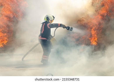 firefighter extinguishes a fire. The hero firefighter stands among the smoke and fire and extinguishes the fire with a stream of water. - Powered by Shutterstock