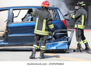 firefighter extinguishing car fire after car accident wearing safety protective gear - Powered by Shutterstock