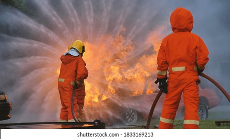Firefighter fighting with flame using fire hose chemical water foam spray engine. Fireman wear hard hat, body safe suit uniform for protection. Rescue training in fire fighting extinguisher