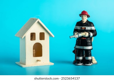 Firefighter figurine standing next to wooden birdhouse on blue background. - Powered by Shutterstock