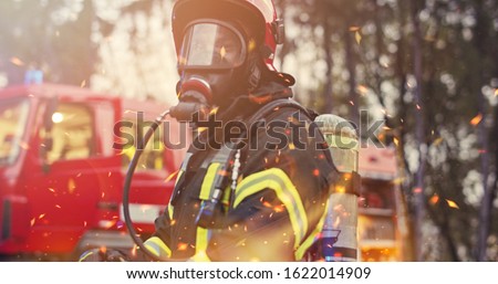 Firefighter in fire fighting operation, fireman in protective clothing and helmet with equipment in action fighting