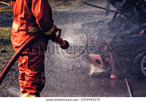 Firefighter in fire fighting suit spraying water,\
Firemen fighting  raging fire with huge flames of burning, Fire\
prevention and extinguishing\
concept