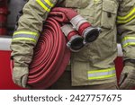 Firefighter in the fire station with hose in the hand. Cropped image