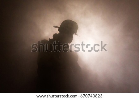 Firefighter in full turnouts silhouetted in smoke