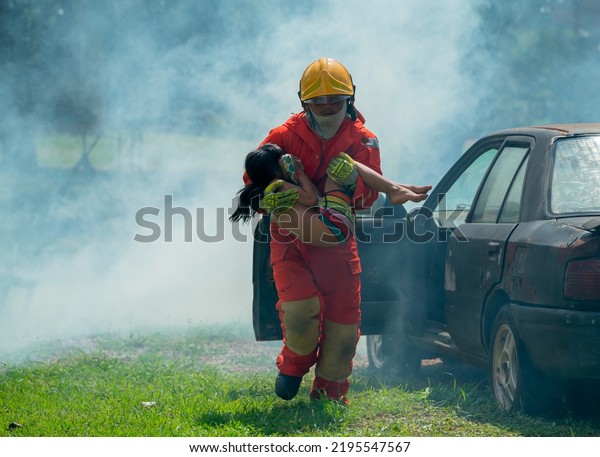 Firefighter help to carry little Asian
girl or children out from car cover with smoke after
fire.