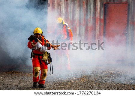 Firefighter hero carrying baby girl out from burning building area from fire incident. Rescue people from dangerous place