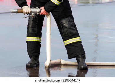 Firefighter holding a fire hose with water in his hands, extinguishing a fire - Shutterstock ID 2206044147