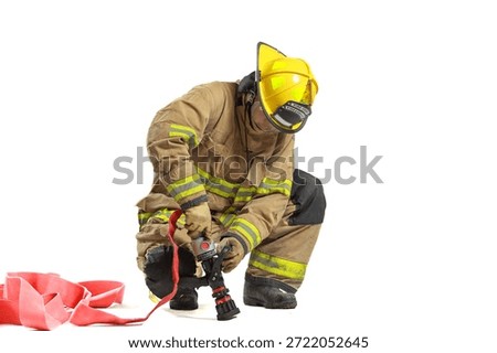 Firefighter kneeling while handling fire hose nozzle, wearing full protective gear and helmet, isolated on white background. Emergency response, fire safety training, rescue, and protective equipment.