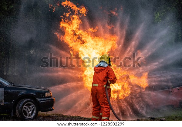 Firefighter Put on a\
 suit Orange Extinguish Car oil fire oil spillage hydrant From\
accident Car crash prevent practice Safety 3 people Control\
Blackout alarm blaze assistance\
heat