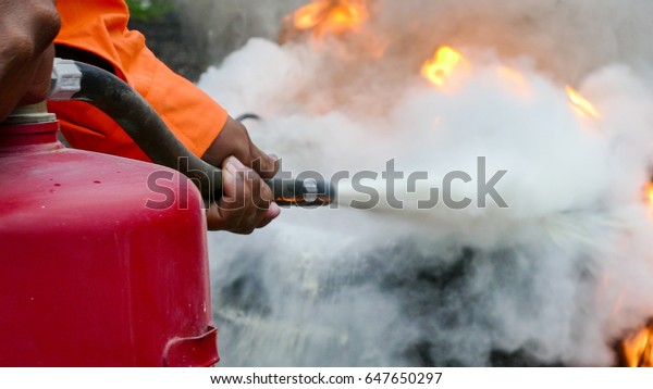 Firefighter putting out a fire with a\
powder type\
extinguisher.\
