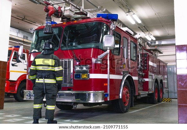 A\
firefighter in special clothes stands in front of a fire truck. A\
fire truck at the fire station. Rescue\
service.
